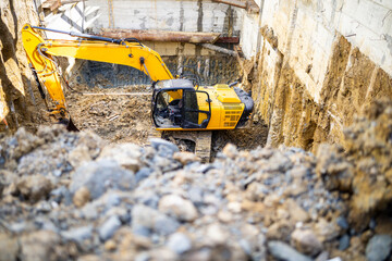 Excavator working on construction site digging foundation in urban area during daylight hours