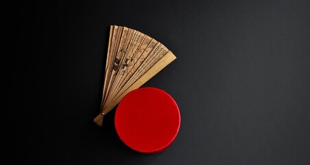 Carved fan. Panda, bamboo symbols. An oriental style fan and a red box, isolated on black. Minimalist composition. Studio shot