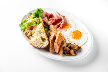 A delicious breakfast plate with crispy bacon, sunny-side-up eggs, grilled sausages, sautéed mushrooms, fresh salad greens, cherry tomatoes, and toasted bread. Perfect for a nutritious morning meal.
