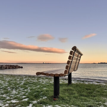 Close-up side view of an empty wooden bench on beach along the Oslo Fjord, Asgardstrand (Aasgaardstrand), Vestfold, Norway