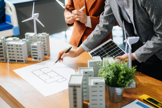 Professionals for a greener future. Showcasing renewable energy solutions with solar panels, wind turbines, and a model house.