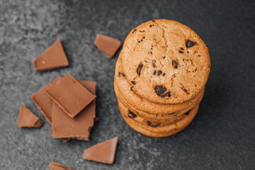 Delicious chocolate chip cookies stacked with chocolate pieces on a dark surface