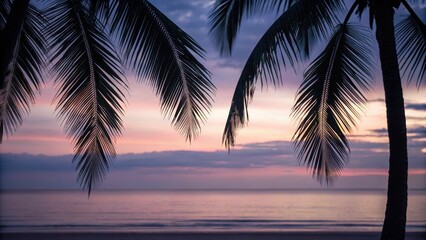 Fototapeta premium Serene beach scene at sunset with palm leaves framing the horizon and calm water reflecting warm colors.