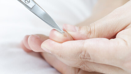 Close up of a beautician using nail scissors to carefully trim toenails, providing a professional...