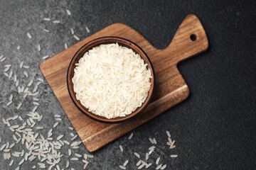 Freshly harvested white rice in a wooden bowl on a cutting board