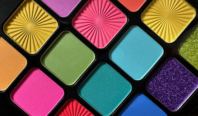 Close-up of a vibrant and colorful eyeshadow palette featuring a variety of shades including pink, yellow, green, blue, purple, and orange