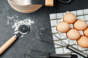 Baking ingredients and tools arranged on a dark countertop for preparation