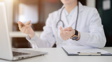 Close up of a doctor with stethoscope explaining with hand gesture while sitting at the white table...