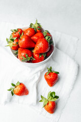Fresh strawberries arranged in a bowl on a white surface