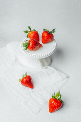 Juicy red strawberries arranged on a small white stand against a light surface
