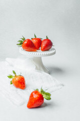 Fresh strawberries displayed on a white cake stand with a soft background