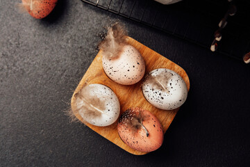 Wooden tray with pastel speckled Easter eggs and feathers. Holiday decoration still life.