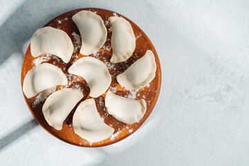 Homemade dumplings arranged on a wooden plate ready for cooking