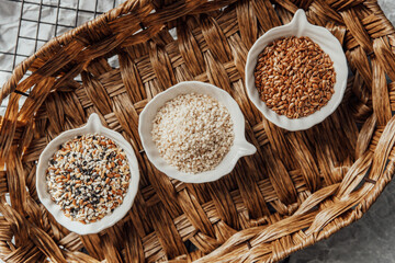 Different types of  seeds displayed in bowls on a woven tray