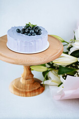 Delicate purple cake topped with fresh berries on a wooden pedestal