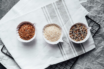 Different seeds displayed in small bowls on a kitchen towel during meal prep