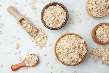 Oats scattered around bowls and a scooper on a light background