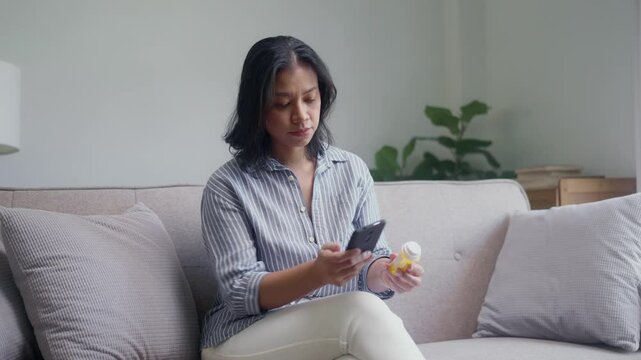 Asian woman hold drug bottle and read information on smartphone