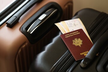 French passport with tickets lies on touristic suitcase close up in airport waiting hall