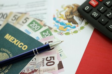 Mexican pesos money bills in big amount lies on table with pen, calculator, passport and tax forms