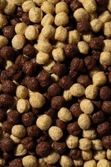 Crispy cereal balls in two colors fill the frame. Strong light highlights texture. Children food branding, packaging, blogs, or product design concept