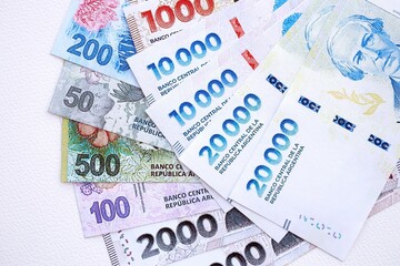 Argentine pesos money bills in big amount lies on white table close up