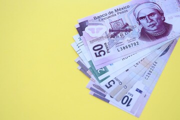 Mexican pesos money bills in big amount lies on yellow color table close up
