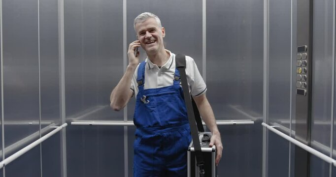 Professional technician having a phone call in the elevator