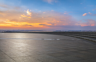 Empty square platform and city skyline with wide river at sunset