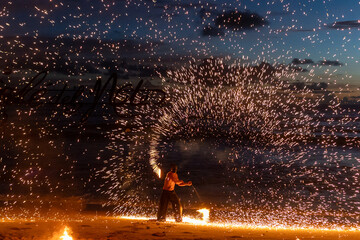 Fire performer lights up the beach, creating beautiful patterns against a sunset backdrop. 