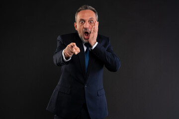 Shocked businessman pointing at camera.