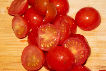 Close up of cut chopped baby tomatoes on a wood chopping board