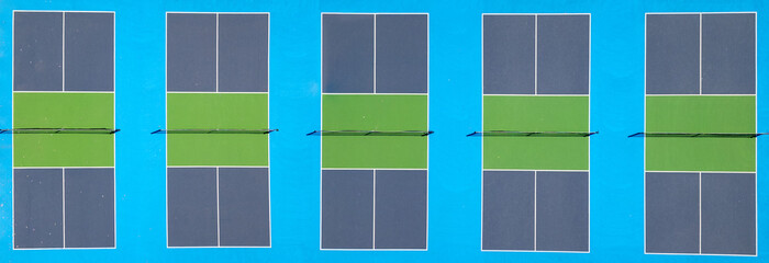 Top-down aerial view of five vibrant pickleball courts with green playing areas and blue borders,...