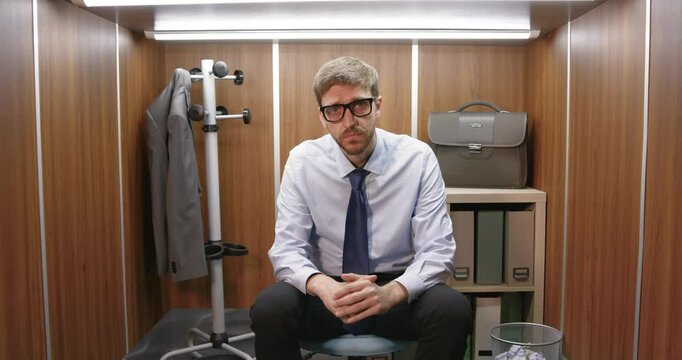 Sad frustrated businessman sitting in a small office