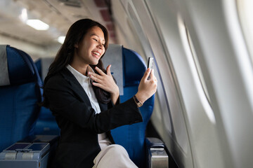 Fototapeta premium Business travel featuring a young woman smiling during a video call on a plane