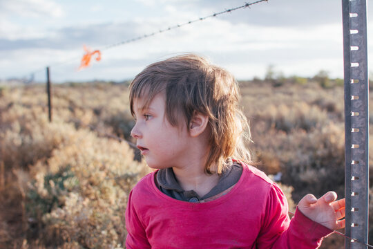 Young girl standing by barbwire fence