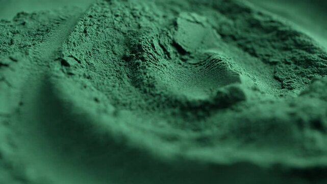 Heap of green spirulina algae powder spins, close up. Green powder super food, macro, rotation. Dietary supplement to improve health. Seaweed superfood concept. Healthy food background