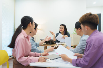 Team of professionals engaged in a collaborative meeting discussing ideas in a bright, modern...