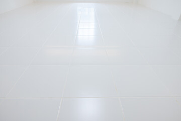 White tile floor with grid line of square texture pattern in perspective at day. Reflection with warm white light. Clean shiny of ceramic surface. Modern interior home design suit for background.