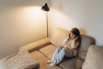 Obraz premium Young Girl Relaxing on Couch While Listening to Music With Headphones