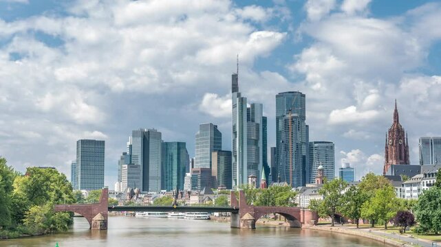 Hyperlapse of Frankfurt's skyscrapers skyline with the bell tower of the Imperial Cathedral of Saint Bartholomew overlooking Alte Brucke, historic stone bridge over the Main River. Frankfurt, Germany