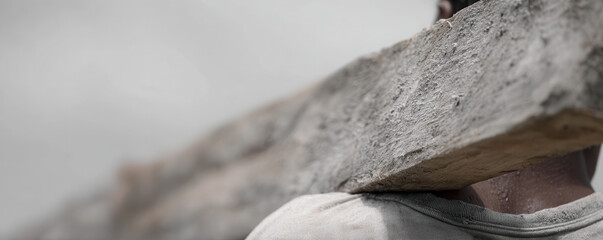 Worker carries heavy beam on their shoulder, showing determination and effort