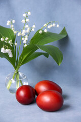 red eggs and a bouquet of lilies of the valley on a blue background, Easter greeting card