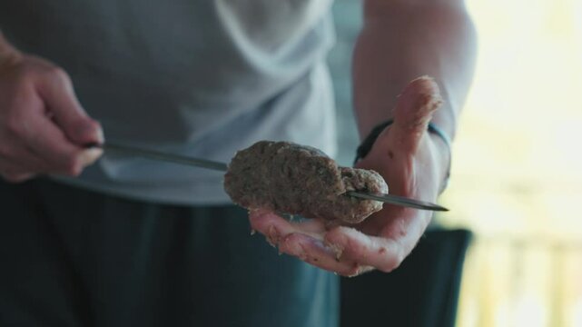 Minced meat carefully shaping around metal skewers during traditional lula kebab preparation, representing mediterranean culinary crafting before grilling delicious turkish-style protein dish