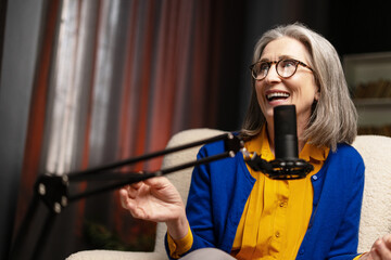 Happy mature woman recording podcast from home