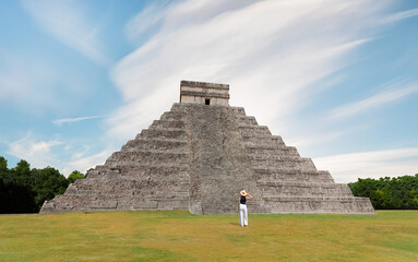 Girl tourist in a hat stands against the background of the pyramid of Kukulcan in the Mexican city of Chichen Itza - Mayan pyramids in Yucatan, Mexico 
