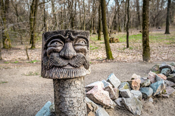 Slavic pagan idol in a green coniferous forest in summer. A wooden statue, an image of a Slavic god. An attribute of religious rites