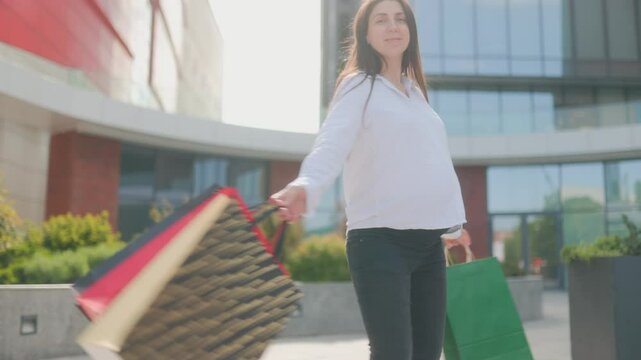 Pregnant woman proudly holding shopping bags after city spree