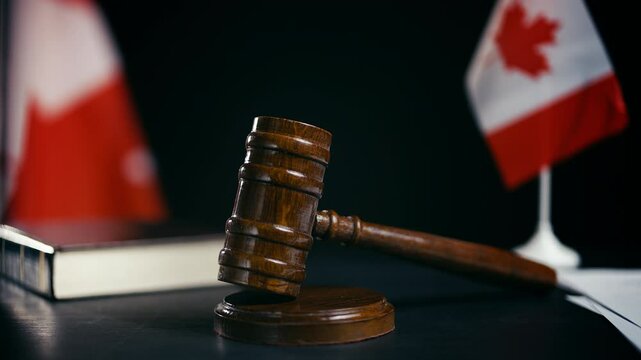 Law books and wooden gavel on desk with Canadian flags, national court system