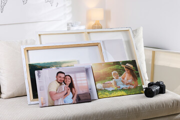 Canvas with different printed photos and camera on sofa indoors